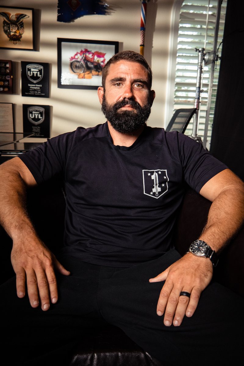 Prime Hall seated in his office in front of Underwater Torpedo League awards
